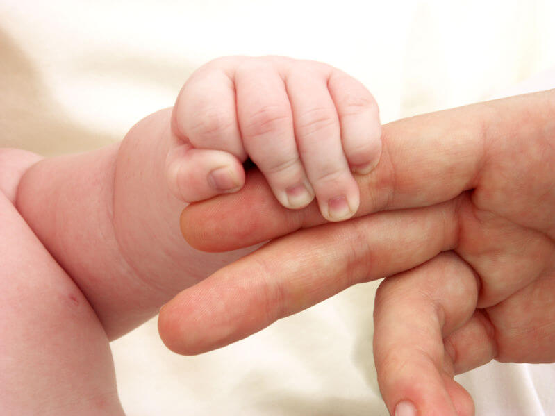Baby holding father's finger